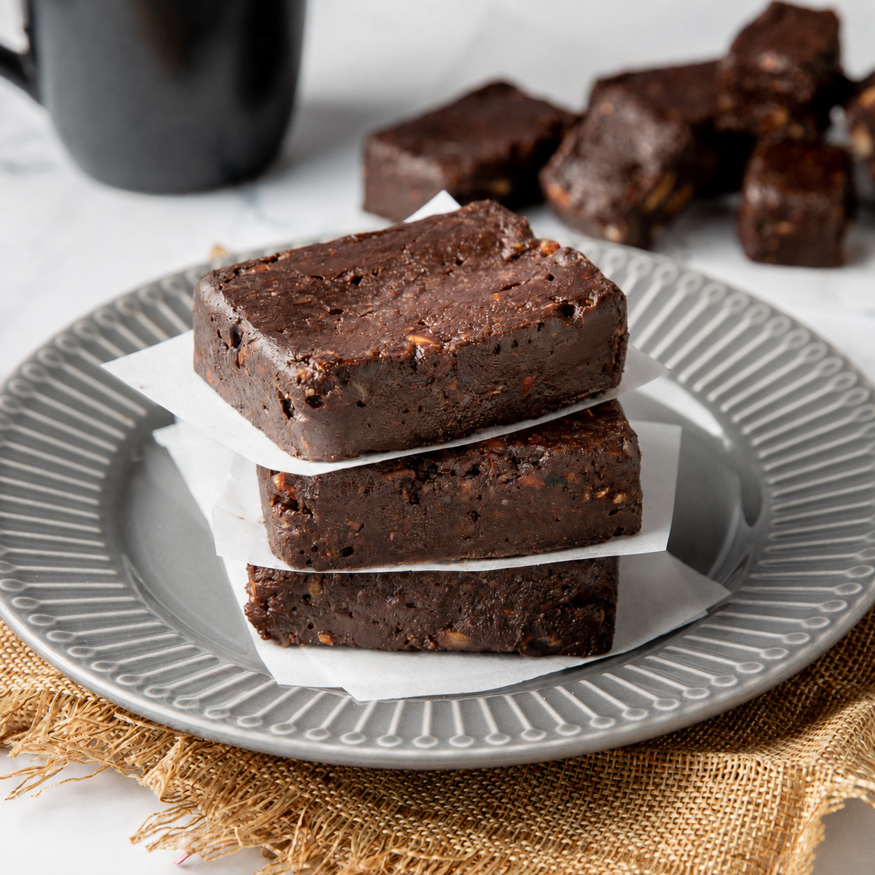 Keto chocolate walnut fudge pieces stacked on a plate