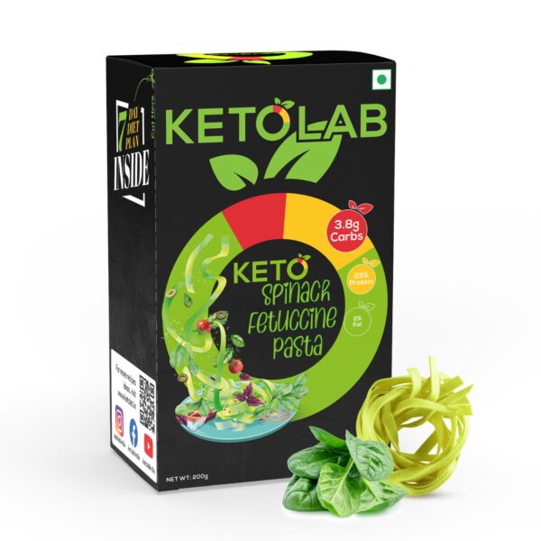 Ketolab Spinach Fettuccine Pasta box with bold branding, showing 3.8g carbs, 23% protein, and 2% fat; accompanied by a coil of green spinach pasta and fresh spinach leaves in the foreground.