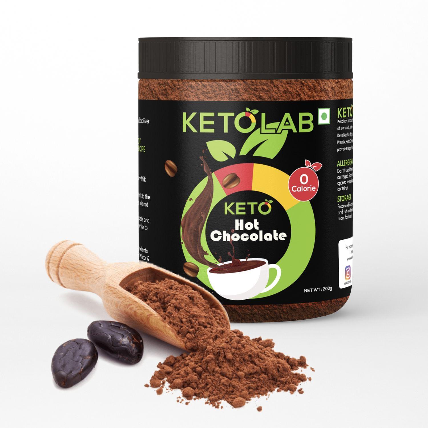 Ketolab Hot Chocolate jar with a zero-calorie label, surrounded by a wooden scoop spilling cocoa powder and two cocoa beans on a white background.